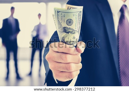 Businessman hand gripping money, US dollar (USD) bills, vintage tone - investment, success and profitable business concepts