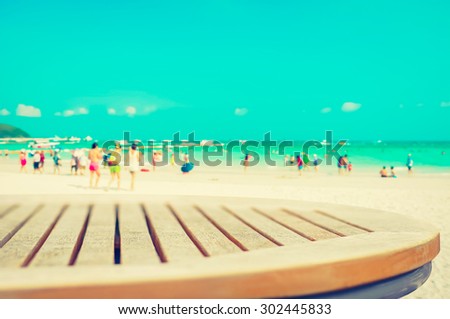 Round wood table top on blur white sand beach background with people, vintage tone - can be used for display or montage your products