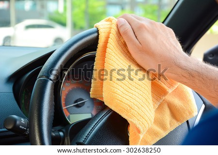 Hand cleaning car steering wheel with microfiber cloth, auto detailing (valeting) concept