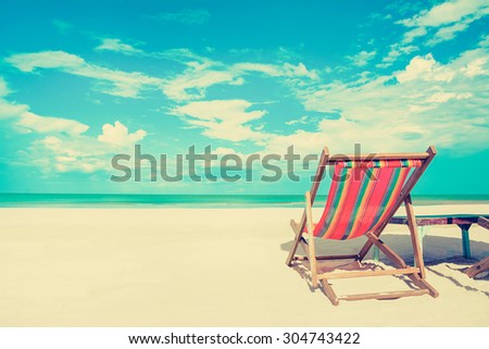 Beach chair on white sand beach in sunny sky background, vintage tone - summer holiday concept