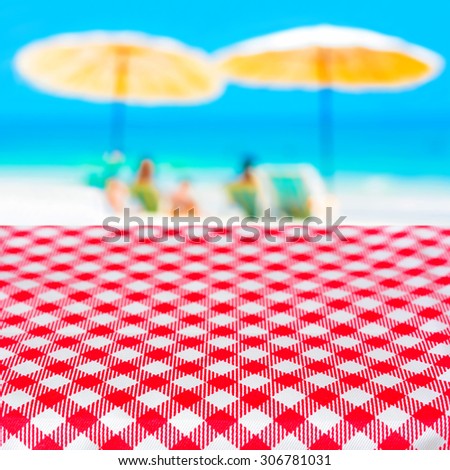 Red checkered table cloth on blurred beach background, summer holiday beach picnic concept - can be used for display or montage your products