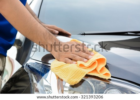A man cleaning car with microfiber cloth, car detailing (or valeting) concept
