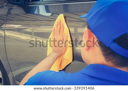 A man polishing car with microfiber cloth, car detailing (or valeting) concept