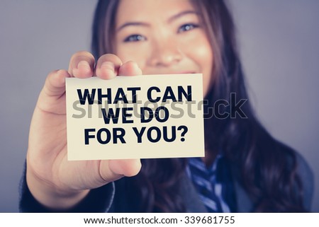 WHAT CAN WE DO FOR YOU? message on the card shown by a businesswoman, vintage tone