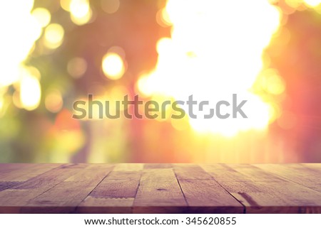 Wood table top on blur bokeh background of sunlight shining through the trees - can be used for display or montage your products