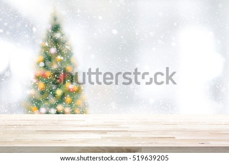 Wood table top on blur Christmas tree and white bokeh in snowfall background