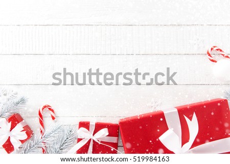 White and red Christmas theme background with gift boxes and decorating elements, top view on wood table, border design