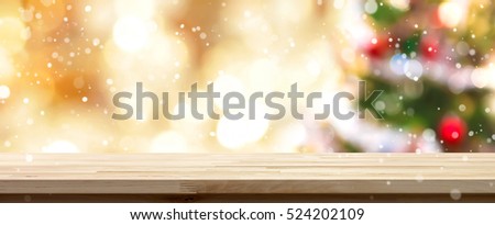 Wood table top on  blur colorful Christmas tree and gold bokeh background with snowfall