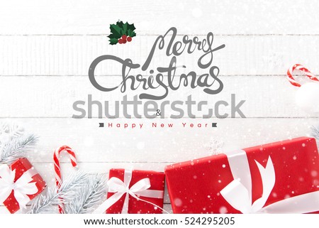 Merry Christmas and Happy New Year text with red gift boxes and ornaments on white wood background, top view
