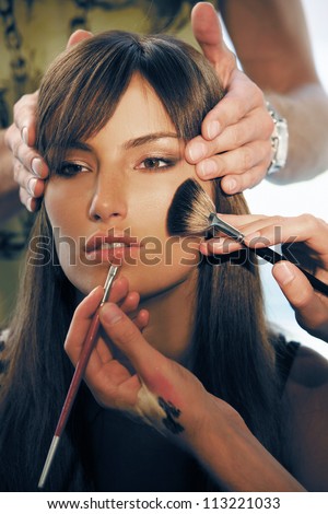 Portrait of a girl.Near the face the hands of makeup artist and hairdresser
