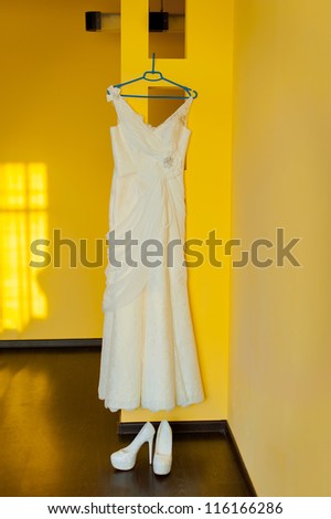 wedding dress and shoes next to the yellow wall in flat
