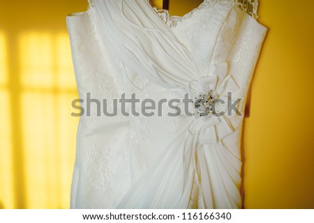 wedding dress hangs on the yellow wall in flat
