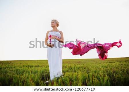 young pregnant woman in a white greek dress with a pink bow
