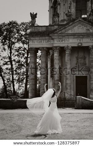 mysterious bride stands next to old church, black and white