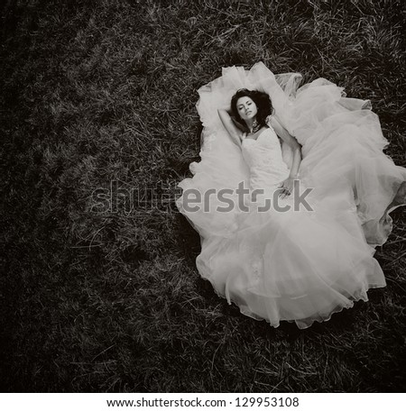 Beautiful bride posing, laying on the grass, high angle shot, black and white