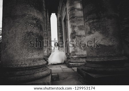 beautiful bride runs between the columns of the old church, black and white