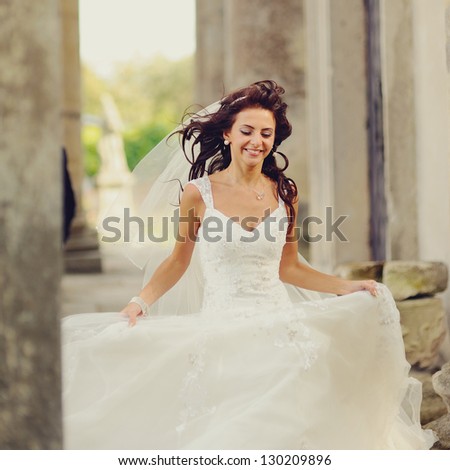beautiful bride runs between the columns of the old church