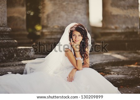 beautiful bride sits on the steps of the old church