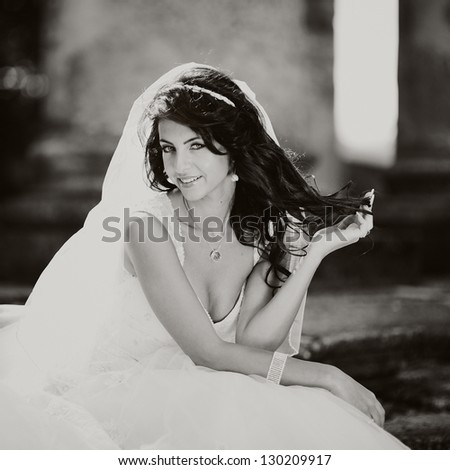 beautiful bride sits on the steps of the old church