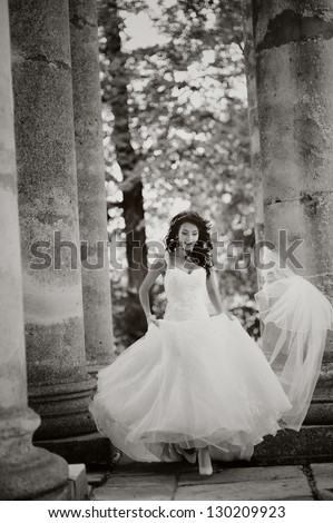 beautiful bride runs between the column left wedding veil on it