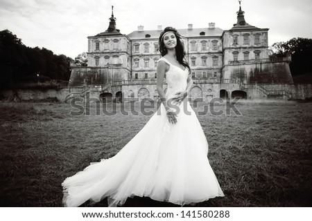Caucasian young bride next to castle in west Ukraine, black and white outside portrait