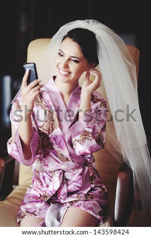 bride looks in to mobile phone using at as a mirror, happy bridal morning