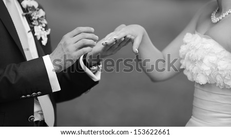 groom holding wedding ring and hand of his bride, hands of a young newly wed couple