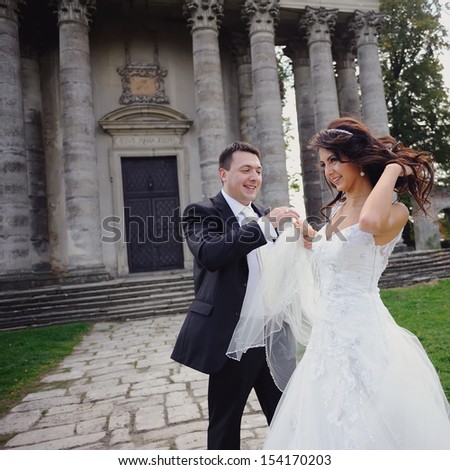 Happy newly wed couple having fun next to old church