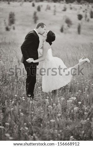 sweet and happy wedding couple in black and white, groom and bride bonding in field,