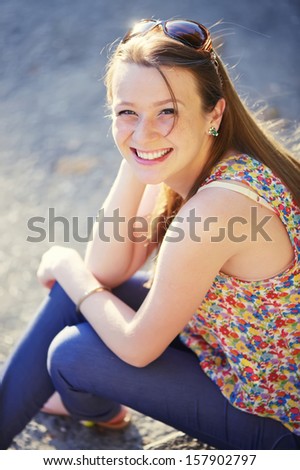 Beautiful Smiling red-haired young woman on steps, outside portrait.