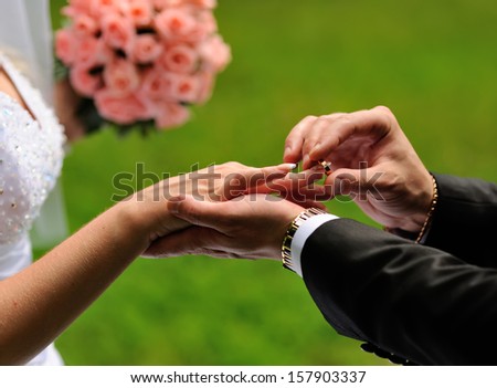 Groom put a ring on finger of his lovely wife. Wedding couple together.