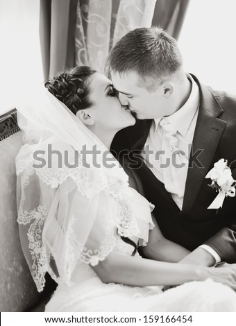 Caucasian wedding couple kissing in restaurant. Black and white picture.