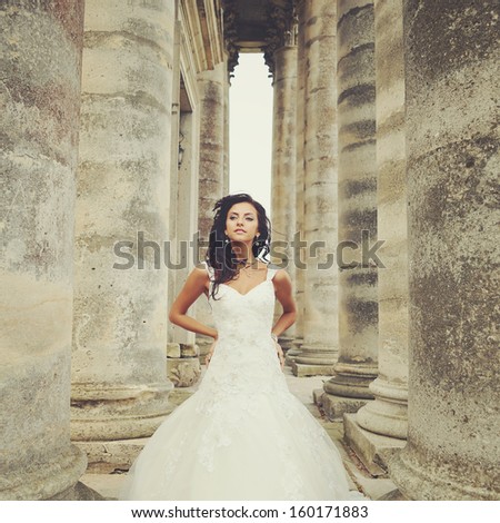 beautiful bride stands between the columns of the an old church