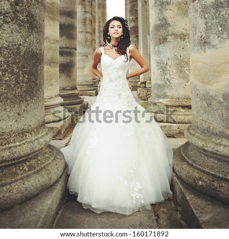 beautiful bride stands between the columns