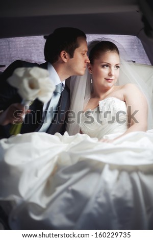 Young couple in limo kissing. Wedding picture.