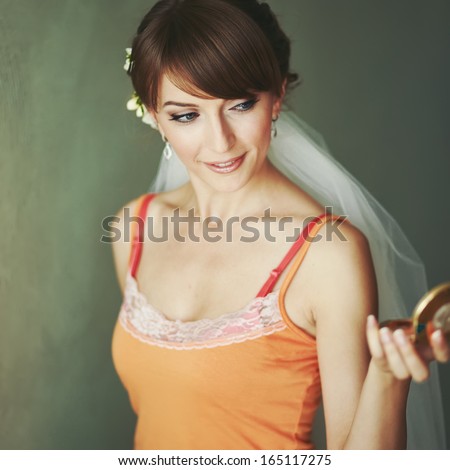 Gorgeous bride looking into mirror, getting ready in the morning.