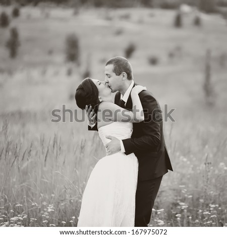 Young groom and bride at field. Wedding couple together in black and white.