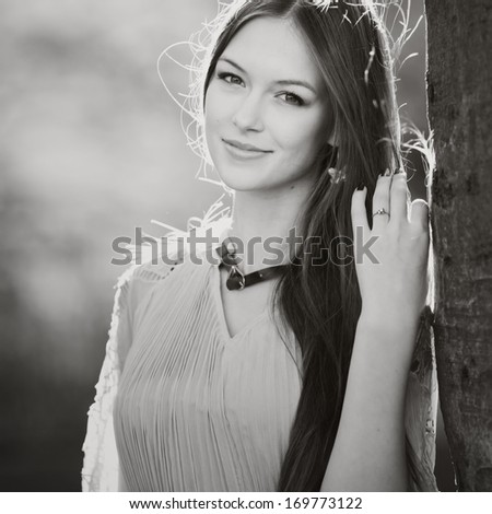 Caucasian woman with long hair wearing dress on sunny summer day. Portrait in black and white.