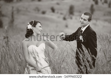 Wedding couple together at field on summer day, black and white.