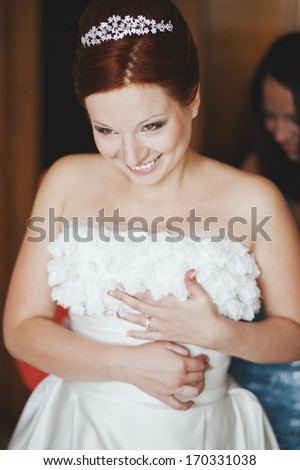 Bridal morning. Lovely red hair bride getting dressed.
