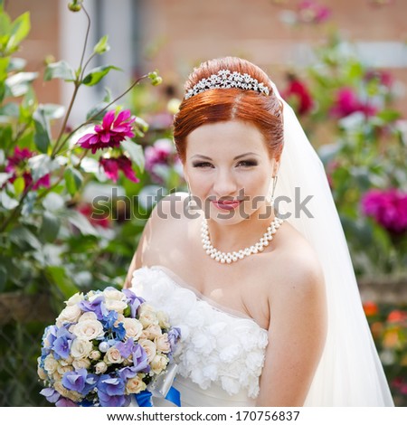 Young lovely red hair young bride posing with flowers.