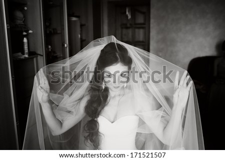 Beautiful young bride playing with veil, waiting for groom. Black and white wedding picture.