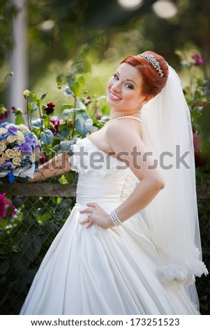 Lovely red hair bride posing with flowers outside. European wedding.