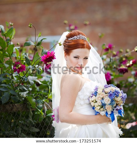 Lovely red hair bride posing with flowers outside. European wedding.