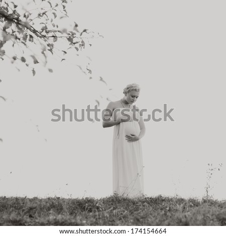 pregnant young woman in field, wearing white dress, black and white picture