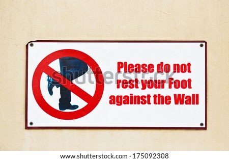 Please do not rest your feet on wall.  Street sign with restriction.