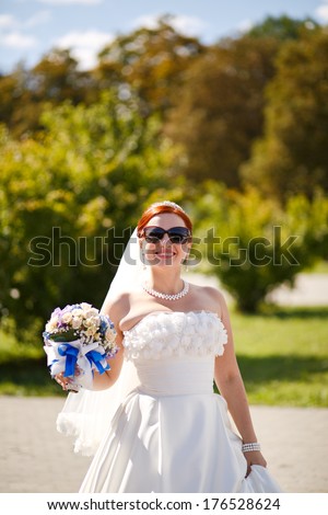Lovely red hair bride posing with flowers outside.