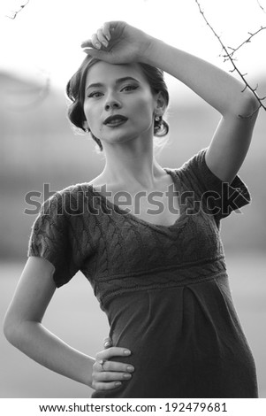 Young woman with retro coiffure posing outside. Portrait in black and white.