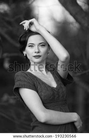Young woman with retro coiffure posing outside. Portrait in black and white.