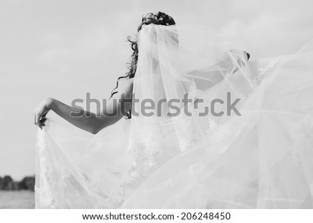 Young caucasian bride playing with veil, spinning around. Wedding black and white picture.